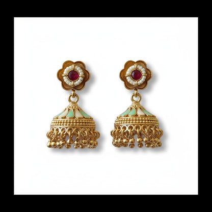 Gold earrings with red and green stones on a white background